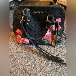 Black Calvin Klein tote with floral design and adjustable strap.